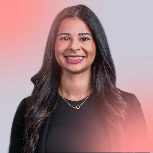 Woman with long black hair wearing a black blouse and a gold neklace is smiling