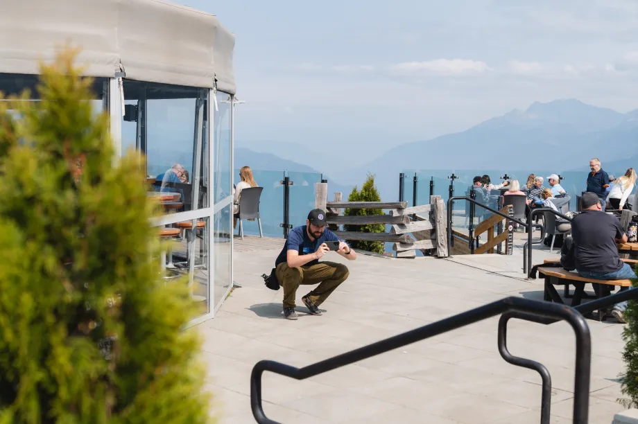 Un homme agenouill&eacute; prend une photo devant un grand portail d'entr&eacute;e avec une rampe incurv&eacute;e.