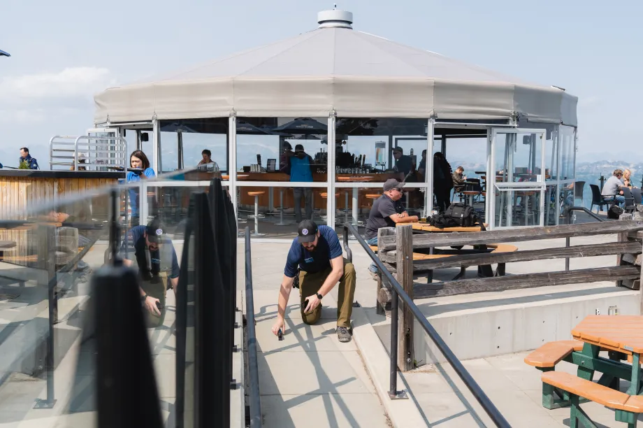 Un homme agenouill&eacute; sur un toit au-dessus d'une rampe, tenant un outil &agrave; la main